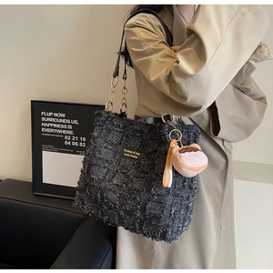 Dettaglio borsa tote in tweed nero con frange e catena in metallo sulla modella