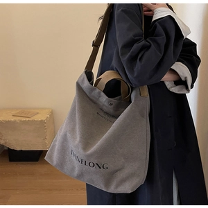 Detail of grey canvas tote bag with brown handles and adjustable wide shoulder strap