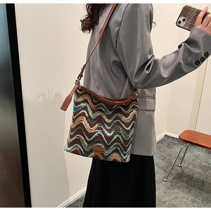 Detail of retro knit bucket bag with brown wavy pattern and leather strap on a model