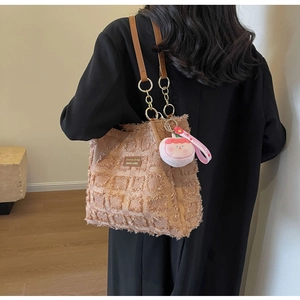Dettaglio della borsa tote in tweed con frange, tracolla a catena e ciondolo fragola