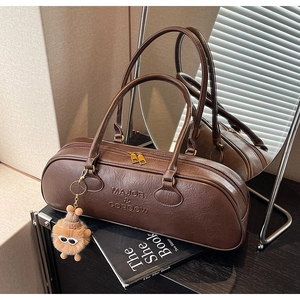 Detail of vintage brown leather bowling bag featuring embossed logo and fuzzy monster charm