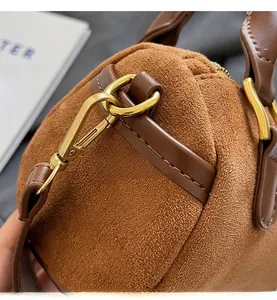Macro view of brown frosted suede texture and golden metal hardware on a Boston bag