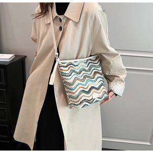 Detail of wave pattern woven bucket bag with cream leather strap on model