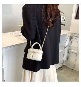 Close-up of a white quilted leather mini bucket bag with gold chain and top handle