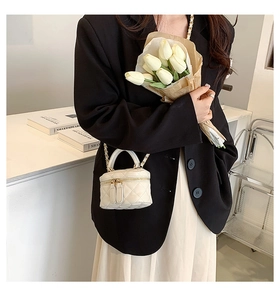 Mini white quilted bucket bag featuring a chain strap and dual zipper detail