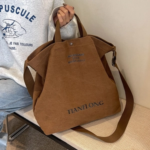 Dark brown canvas tote bag with adjustable shoulder strap and lettering design