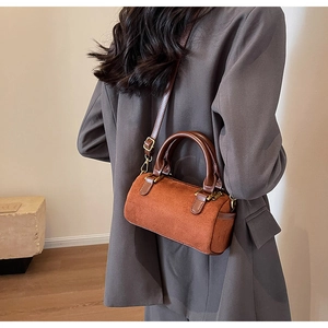 Detail of vintage brown suede Boston cylinder bag with leather handles and gold hardware
