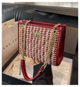 Macro shot of red and white tweed bag with gold turn-lock closure in a gift box