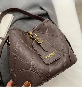 Gros plan du sac seau en cuir matelassé marron chocolat avec fermoir doré