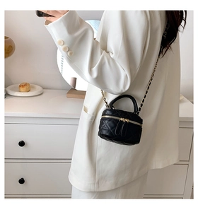 Close-up of a black quilted mini bucket bag with gold chain strap and top handle design