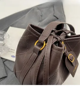 Gros plan du sac seau matelassé marron avec anneau doré et étiquette en cuir embossé