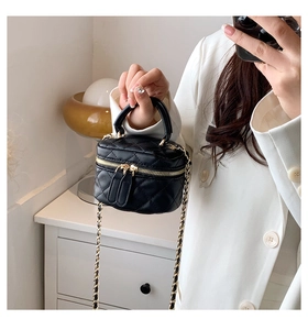 Detail of black quilted PU leather crossbody bag with gold-tone chain strap and zipper