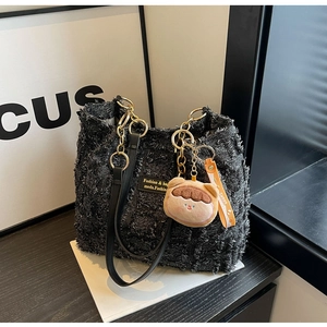 Dettaglio della borsa tote in tweed con catena dorata e ciondolo a orsetto