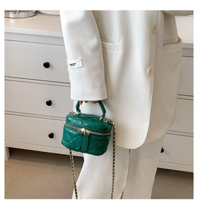 Detail view of mini forest green quilted leather bucket bag with gold chain strap