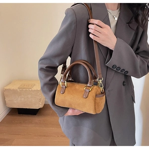 Detail of vintage Boston barrel bag in brown matte suede with leather straps on a model