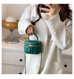 Detail of dark green quilted mini bucket bag with gold chain strap and dual zipper closure