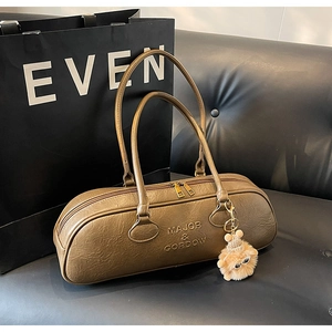 Close-up of vintage brown leather bowling bag with brand embossing and plush ball charm