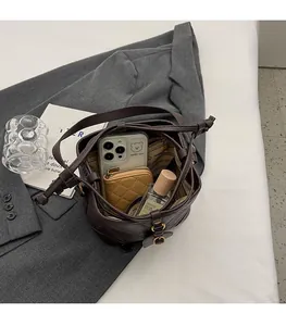 Détail du sac seau matelassé marron foncé montrant l'intérieur spacieux pour l'essentiel