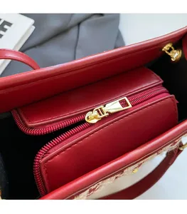 Close-up of red leather wedding handbag with gold metal zipper and black lining