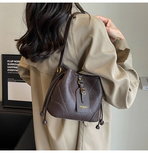 Détail du sac seau matelassé en cuir marron foncé avec accents dorés et cordon de serrage