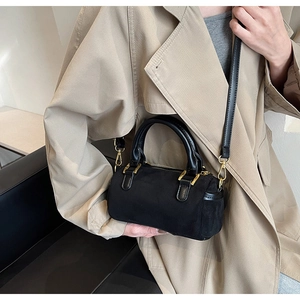 Detail of a black frosted Boston bag worn over the shoulder on a khaki trench coat