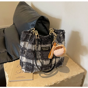 Dettaglio della borsa tote a scacchi con frange di peluche, tracolla e catena dorata