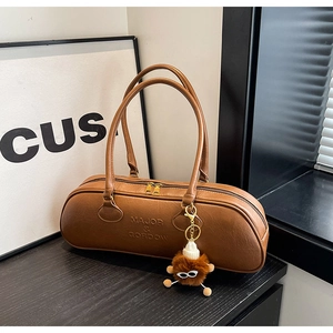 Detail of a brown Boston bag with embossed brand logo and a cute plush charm accessory