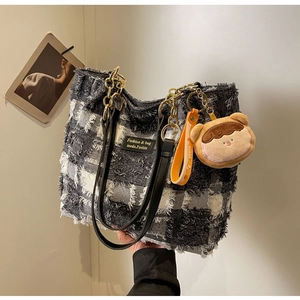 Dettaglio della borsa tote in denim a scacchi con bordi sfrangiati e ciondolo orsetto