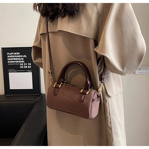 Brown frosted leather Boston bag styled with a khaki trench coat for a retro autumn look