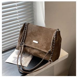 Détails de la texture du cuir brossé marron et chaîne argentée du sac cabas