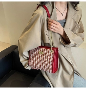 Red and white tweed handbag with gold lock shown on model wearing a trench coat