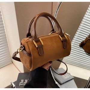 Macro shot of dark brown frosted suede Boston bag with golden hardware and leather strap