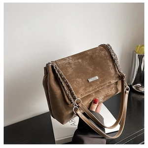 Détail du sac cabas marron vintage avec chaîne argentée et logo de la marque en métal