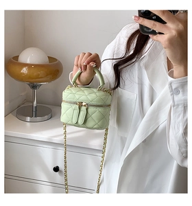 Detail of mint green quilted mini vanity bag with gold chain strap in a stylish room
