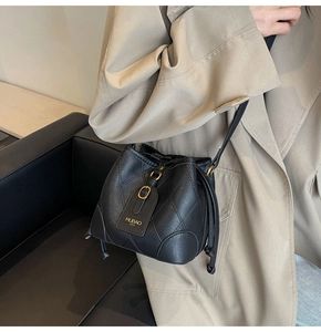 Détail du sac seau noir en cuir matelassé avec ferrures dorées et cordon de serrage