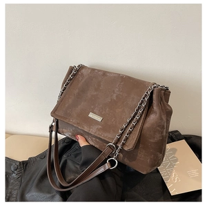 Gros plan du sac cabas marron vintage avec texture mate, chaîne argentée et logo en métal