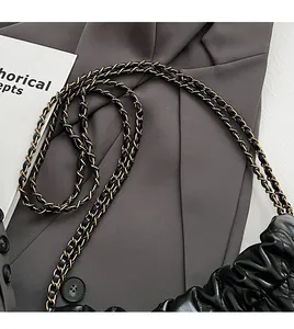 Detail of black leather pleated cloud bag with elegant gold-tone metal chain strap