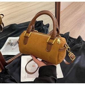 Close-up of retro mustard yellow suede Boston bag with brown handles and gold zipper