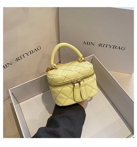 Detail of light yellow quilted mini bucket bag with gold zippers and top handle