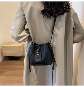 Détail du sac seau noir matelassé avec fermeture à cordon et étiquette de la marque