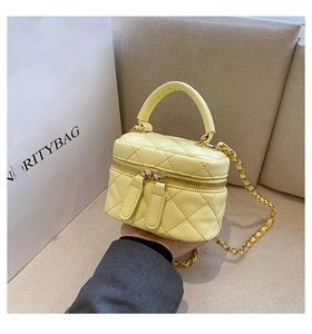 Detail view of mini yellow quilted box bag with leather-interwoven chain strap and handle