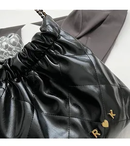 Detailed macro view of black quilted faux leather handbag with gold chain and metal charms