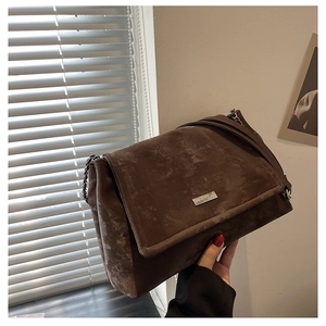Détail du sac cabas vintage en daim marron avec chaîne argentée et plaque logo en métal
