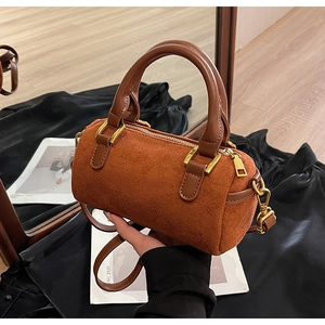 Close-up of caramel leather Boston bag with orange suede texture and gold hardware