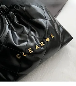 Close-up of black quilted leather texture with gold CLEAR K logo and heart metal detail