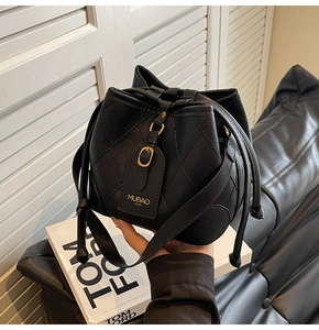 Détail du sac seau matelassé noir avec cadenas doré et fermeture à cordon de serrage