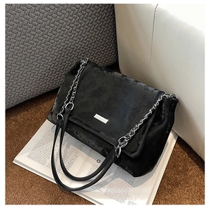 Détail du sac cabas en velours noir avec chaîne argentée et logo métal sur magazine