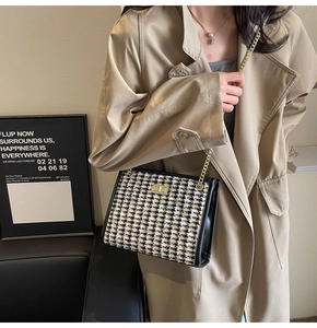 Detail of classic black and white tweed shoulder bag with gold chain strap and turn lock