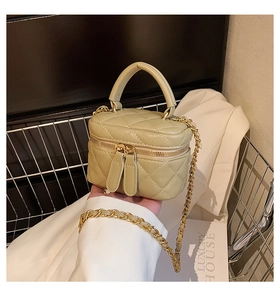 Detail of light green quilted mini bucket bag with gold zippers and chain strap