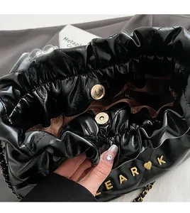 Close-up of black pleated cloud bag with gold magnetic buckle and EAR K metal logo detail